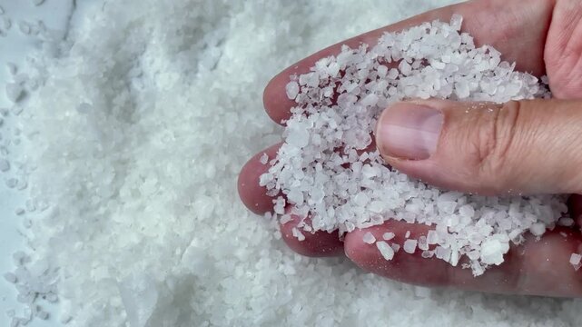 Fingers touching organic white salt crystals for spa and culinary concept