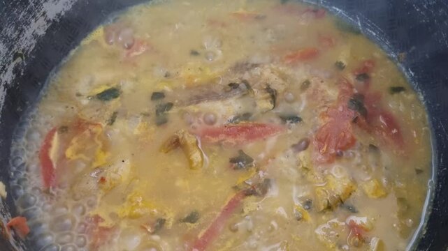 Close-Up of Fresh Pollock Fillets Simmering in Seasoned Broth with Tomatoes, Herbs, Rising Steam, and Homemade Spices in Cooking Pot