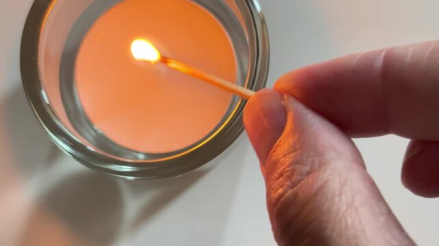 Match igniting a candle wick for cozy atmosphere and relaxation