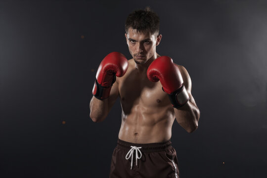 Powerful Boxer in Red Gloves Ready for Combat Against Dark Background, Generative AI
