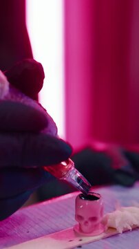 Tattoo, machine and hands of person with ink cap to prepare for artwork, design and body modification. Parlor, aesthetic and artist with pen, pigment and tools for permanent art, service and start