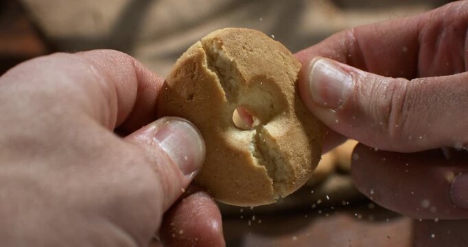 Slow Motion Of Hands Breaking Traditional Cookie. Close-up of hands breaking a freshly baked cookie, highlighting texture, homemade baking and delicious snack.