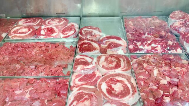 Fresh Meat Display at a Grocery Store Counter.Glass-Topped Refrigerated Meat Counter with Various Cuts of Meat in a Supermarket
