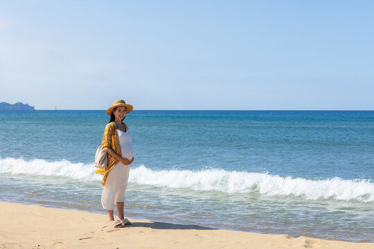 Pregnant woman posing on sandy beach in summer