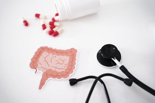 A stethoscope, a symbol of the colon, and pills coming out of a bottle. Treatment and prevention of constipation and diarrhea. The concept of colon and digestive system health. Colon Cancer Awareness 