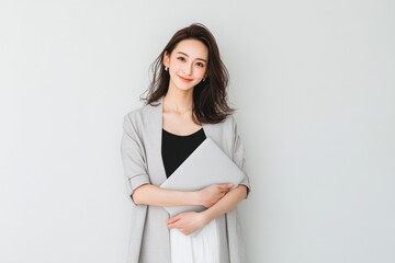 Fototapeta premium Confident Young Professional Woman Holding Laptop, Smiling Softly Against a Clean White Background