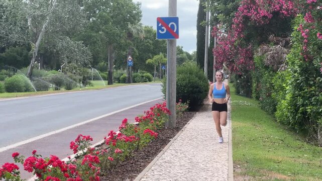 Female runner in activewear burning calories with a cardio workout. Sporty woman jogging running on city park bridge outdoors. Woman exercising with earphones on in the morning. Copy space Stock Photo