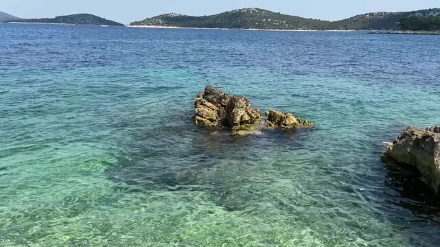 Clear blue water and rocky coastline view during a sunny day at the beach in Croatia near the islands