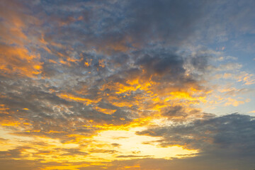 Fototapeta premium Golden Sunset Sky with Dramatic Clouds,A breathtaking view of a vibrant golden sunset sky filled with textured clouds, creating a peaceful and inspiring atmosphere.