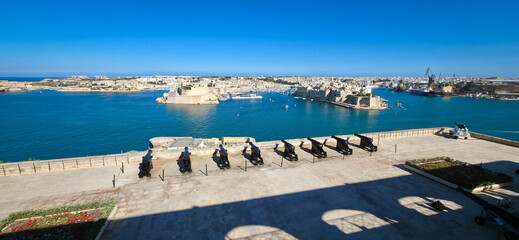 Fototapeta premium View of the cannon-lined square from the Upper Barrakka Gardens in Valletta, Malta, overlooking the Three Cities : Isla, Birgu, and Kalkara.