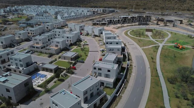 Drone orbital view of Queretaro residential neighborhood development featuring three story duplex units apartment buildings and community park space