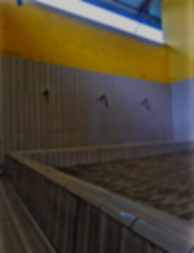 Defocused of an Islamic ritual ablution (wudhu) facility inside a mosque. The abstract composition features a vibrant yellow wall against a striped backdrop.