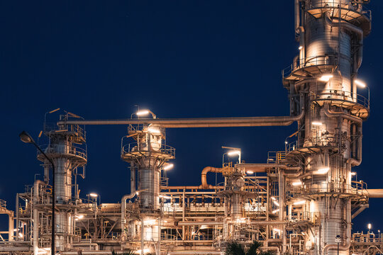 Oil Refinery Plant Illuminated with Glowing Lights and Distillation Column Pipe and Industrial Towers