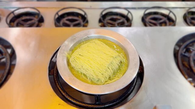 Cooking Process &ndash; Frying Traditional Turkish Kadayıf Pastry in a Large Skillet on a Stove Top.Frying Kadayıf on the Stove &ndash; Turkish Dessert Preparation