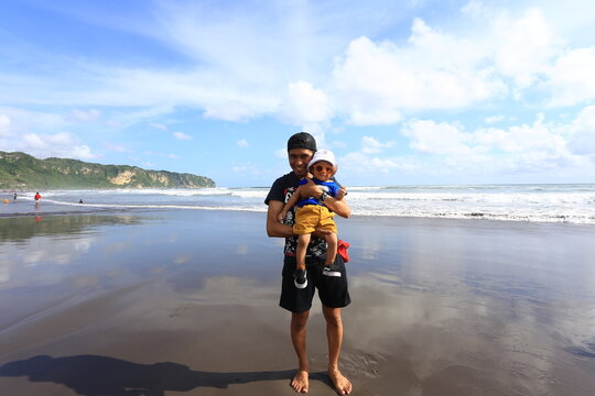 June 15 2019 Yogyakarta Indonesia Man Holding Young Child Standing on Wet Sand Mirror Reflection at Parangtritis Beach