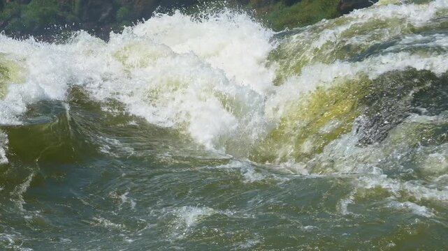 Turbulent green water crashing and splashing in a powerful river. White foam forming on the surface as the strong current moves downstream