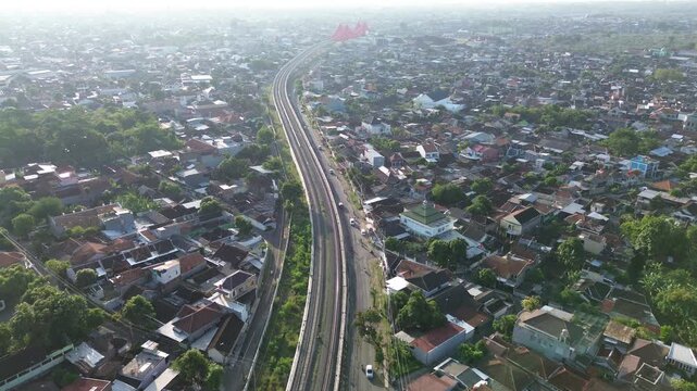 Aerial view of railway tracks cutting through Surakarta city center at sunset, Solo, Central Java, Indonesia. Drone shot of urban railroad infrastructure during warm afternoon light.