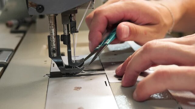 Tailor's hands cutting thread with scissors after sewing