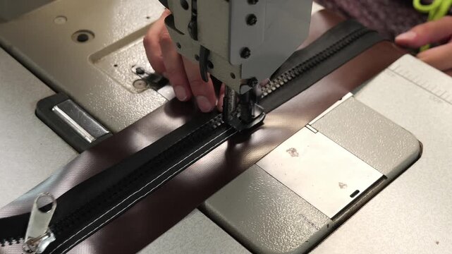 Industrial sewing machine stitching a black zipper