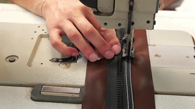 Industrial sewing machine stitching zipper on brown fabric