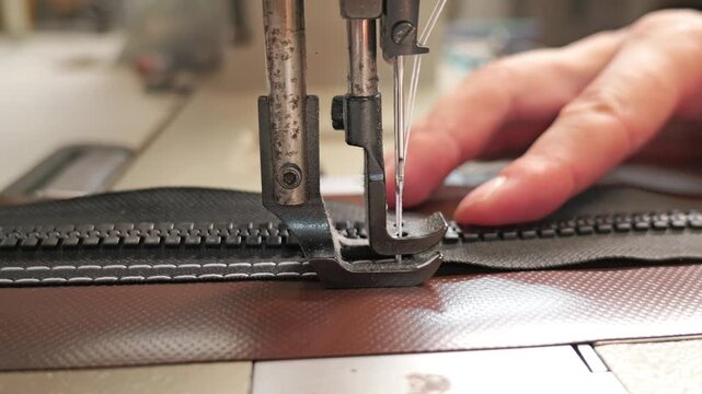 Close up of industrial sewing machine stitching zipper