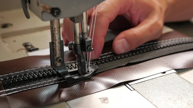 Professional seamstress sewing zipper on brown fabric