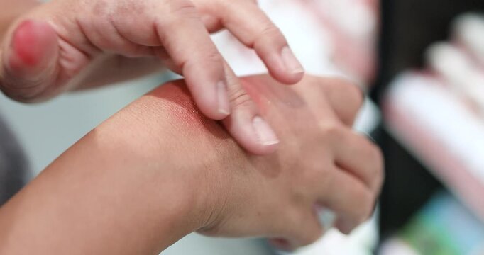 Woman testing a cosmetic product on the back of her hand in a beauty store. Skincare, makeup, beauty shopping, product texture, and consumer choice, close-up