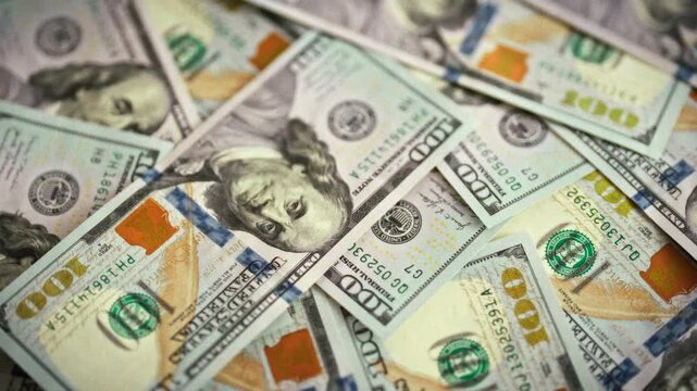 Top-down view shows fresh one-hundred-dollar banknotes spread across flat surface, emphasizing crisp cash. arrangement underscores physical money's role as tangible alternative to digital payments