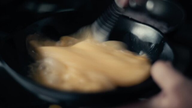 Cinematic close up of whisking and scrambling eggs with a spatula in a hot frying pan.