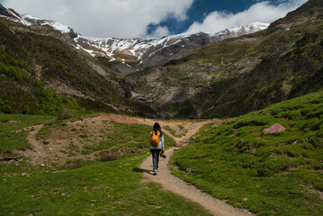 Fototapeta premium A young girl hiking alone in the Pyrenees, Pineta Valley, Monte Perdido, Camino de los Llanos de la Larri, Aragón, Huesca, Spain