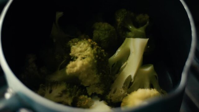 Close up of fresh green broccoli florets cooking and steaming inside a pot.