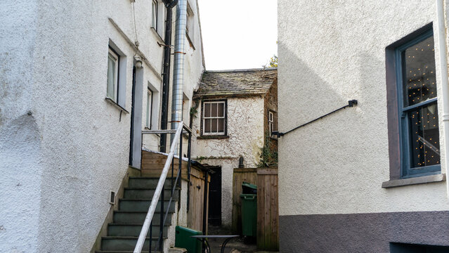 A two-story stone/plastered building with an attic and an enclosed backyard, featuring an exterior staircase leading to the upper level