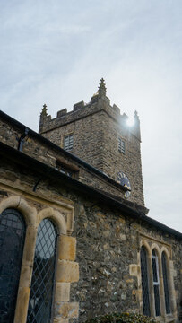 St Michael & All Angels Church, Hawkshead, Lake District, England. A stone church with a distinctive crenellated tower and a clock on it
