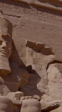 Close-up of giant Ramesses II colossi carved into rock facade at Abu Simbel temple, Egypt. Dramatic upward view of ancient sandstone pharaoh statues. Travel and history.