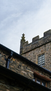 St Michael & All Angels Church, Hawkshead, Lake District, England. A stone church with a distinctive crenellated tower and a clock on it