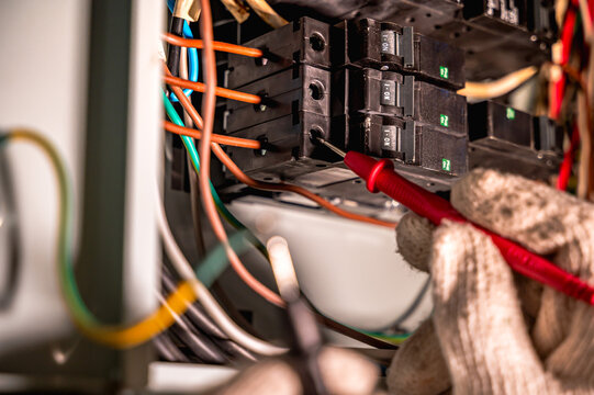 Close up unrecognized certified electrician wearing gloves preparing residential electrical panel for a second electric vehicle charger installation