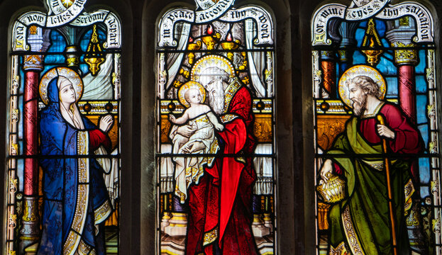 A three-panel stained-glass window depicting a close-up of the biblical scene of the Presentation of the Lord