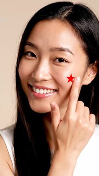 Radiant Skincare Routine: Smiling Asian Woman Pointing at a Red Star-Shaped Pimple Patch on Her Cheek, Ideal for Beauty Blogs and Skincare Product Marketing Vertical. Video. Portrait Orientation.