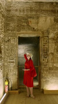 Woman in a red dress exploring the temple in Abu Simbel, Egypt.