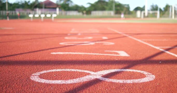 Close up of number 8 on red running track with blurry joggers background