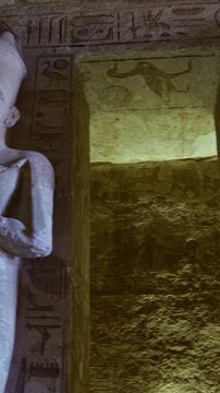 Grand hypostyle hall of Abu Simbel temple, Egypt, with two rows of colossal Ramesses II osiride figures flanking painted ceiling covered in vultures, cartouches and hieroglyphics.