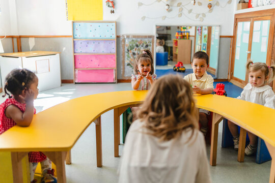Children learning and playing with teacher in kindergarten