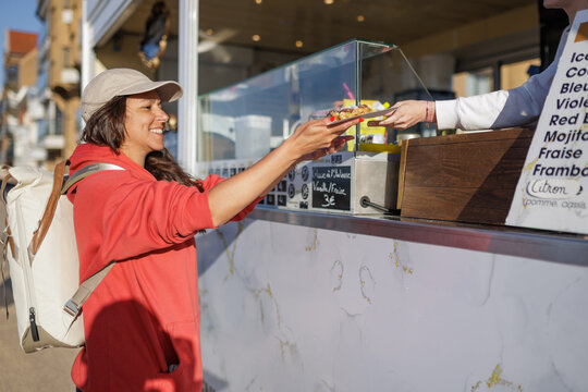 Smiling woman receiving fresh waffle at outdoor street food truck