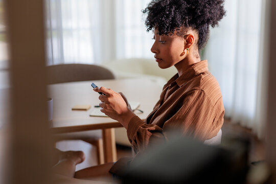 Woman using mobile phone at table with notebook and pen.