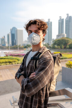 Masked man with backpack in city park coping air pollution 