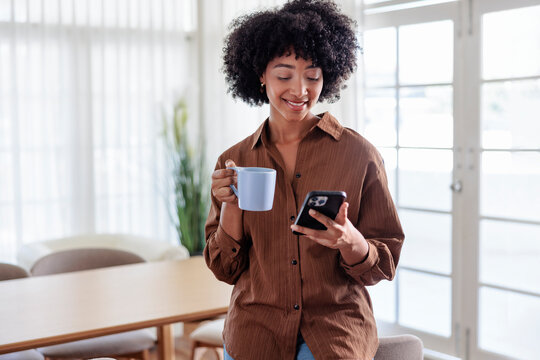 Woman with coffee and mobile phone in bright room.