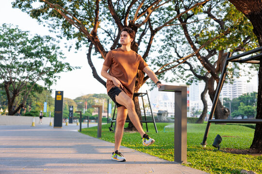 Man worm up legs in park before run.