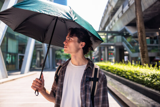 Man with his  umbrella in city hiding from the sun