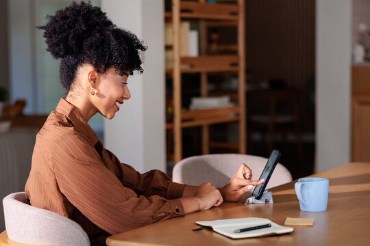 Woman smiles while using phone at table with notebook.