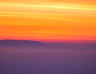 Obraz premium Vibrant orange sunset over landscape horizon.